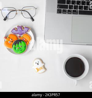 Biscuits d'Halloween, café chaud et ordinateur portable sur fond blanc. Joyeux Halloween, achats en ligne, Bonjour octobre, automne automne automne, fête, fête a Banque D'Images