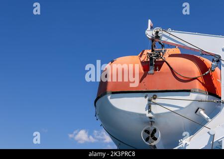 Bateau à moteur de sauvetage orange avec lequel chaque traversier de passagers est équipé, arrière-plan avec ciel bleu clair le matin d'été Banque D'Images