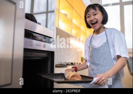 Bonne jeune femme de ménage qui fait un gâteau dans la cuisine Banque D'Images