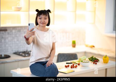 Fille prenant un selfie dans la cuisine Banque D'Images