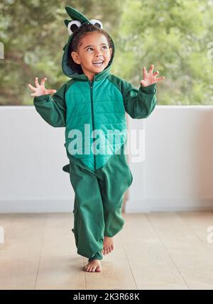 Enfant, souriez et excité dans le costume de dinosaure d'halloween à la maison jouant le rôle et s'amuser à la fête. Un enfant heureux jouant avec un personnage fantastique Banque D'Images