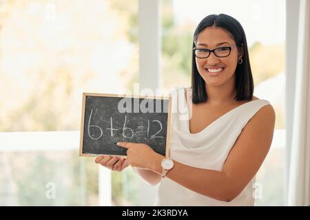 Heureux, sourire et portrait d'un professeur de mathématiques avec un tableau pointant vers une équation dans sa salle de classe. Bonheur, femme intelligente et jeune debout dans un Banque D'Images