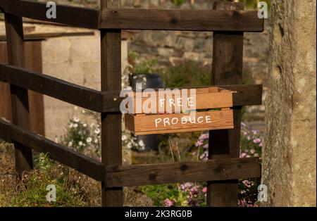 Une boîte en bois attachée à une clôture dans le Yorkshire, en Angleterre. La boîte contient des pommes excédentaires qui sont offertes gratuitement à quiconque passe. Banque D'Images