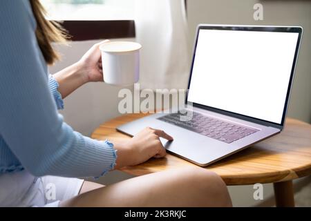 Image de maquette d'une femme travaillant et tapant sur un ordinateur portable avec écran blanc vierge à la maison Banque D'Images