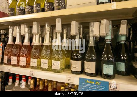 Bouteilles de vin et d'alcool sur une étagère dans un supermarché avec des étiquettes de sécurité sur chaque bouteille pour arrêter le levage de magasin au Royaume-Uni Banque D'Images