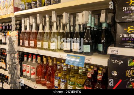 Bouteilles de vin et d'alcool sur une étagère dans un supermarché avec des étiquettes de sécurité sur chaque bouteille pour arrêter le levage de magasin au Royaume-Uni Banque D'Images