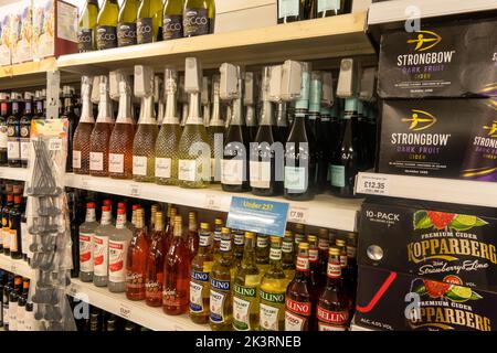 Bouteilles de vin et d'alcool sur une étagère dans un supermarché avec des étiquettes de sécurité sur chaque bouteille pour arrêter le levage de magasin au Royaume-Uni Banque D'Images