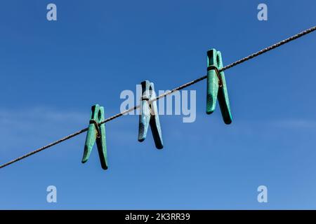 Trois épingles à linge en plastique accrochées à une corde à linge contre un ciel bleu. Banque D'Images