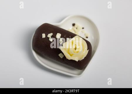 Patate de gâteau sur une soucoupe en forme de coeur. Décoration avec crème au beurre. Sur fond blanc. Gros plan. Banque D'Images