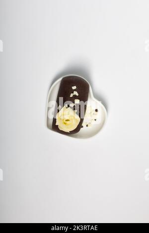 Patate de gâteau sur une soucoupe en forme de coeur. Décoration avec crème au beurre. Sur fond blanc. Gros plan. Banque D'Images