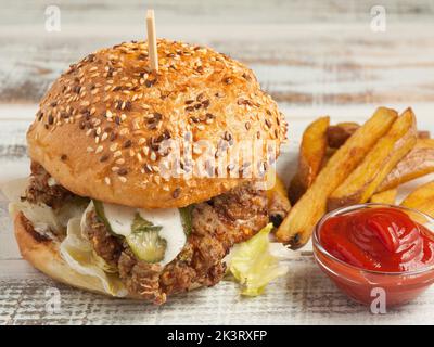 Hamburger savoureux avec frites au poulet, concombres, pommes de terre et sauce tomate Banque D'Images