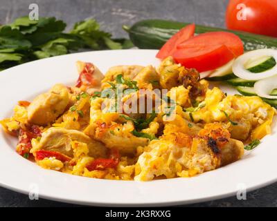 délicieux mélange d'œufs avec du poulet décoré de légumes verts sur une assiette blanche Banque D'Images