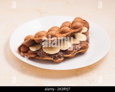 Gaufre douce de Hong Kong avec pâte de banane et de chocolat sur une assiette blanche Banque D'Images