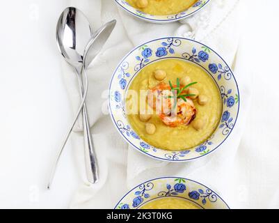 Délicieuse soupe à la crème de pois chiches décorée de crevettes. Arrière-plan blanc. Directement au-dessus. Alimentation saine, alimentation, recette ou concept de menu. Banque D'Images