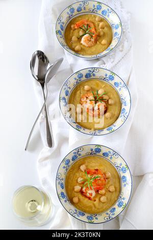 Délicieuse soupe à la crème de pois chiches décorée de crevettes. Arrière-plan blanc. Directement au-dessus. Alimentation saine, alimentation, recette ou concept de menu. Banque D'Images