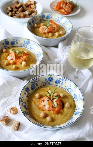 Délicieuse soupe à la crème de pois chiches décorée de crevettes. Arrière-plan blanc. Directement au-dessus. Alimentation saine, alimentation, recette ou concept de menu. Banque D'Images