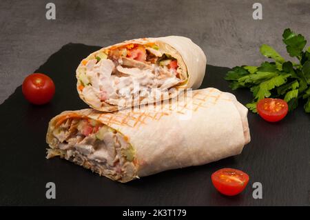 Grand Shawarma savoureux avec légumes et poulet sur fond sombre Banque D'Images