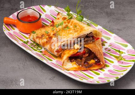 Délicieux burrito mexicain avec du bœuf et des légumes et de la sauce chaude Banque D'Images