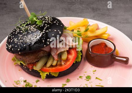 Hamburger noir savoureux avec bœuf, légumes, sauce tomate épaisse et frites Banque D'Images