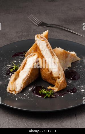 crêpes sucrées avec fromage cottage et confiture sur une assiette sombre Banque D'Images
