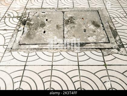 La couverture en béton de trou d'homme sur le pavé de la voie de brique près de la rue dans la ville, vue de face avec l'espace de copie. Banque D'Images