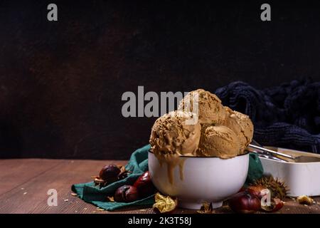 Glace épicée d'automne au goût de châtaignes grillées, aux épices, sur un fond de bois avec des châtaignes fraîches et grillées Banque D'Images