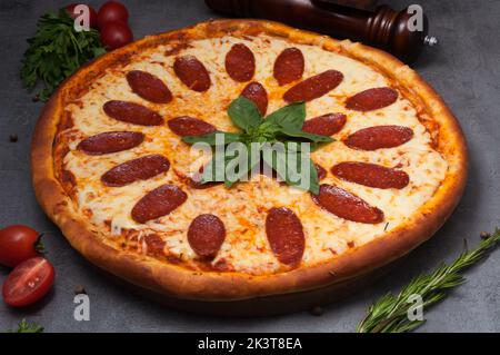 savoureuse pizza au pepperoni au fromage mozzarella décoré de basilic Banque D'Images
