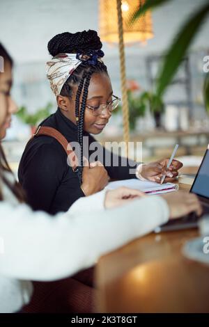 Deux étudiantes multiculturelles s'assoient dans un café et étudient pour l'examen final. Banque D'Images
