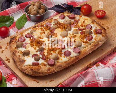 pizza savoureuse avec saucisses, champignons et mozzarella sur une planche de bois Banque D'Images