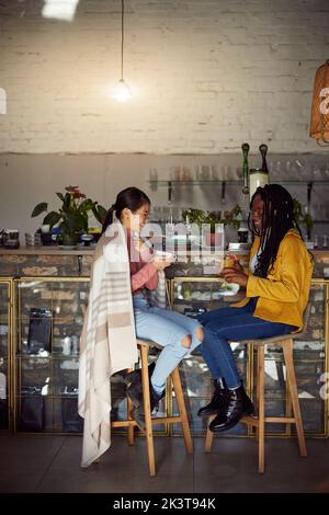 Une femme multiculturelle se trouve dans un bar, sert des boissons et bavarde. Banque D'Images
