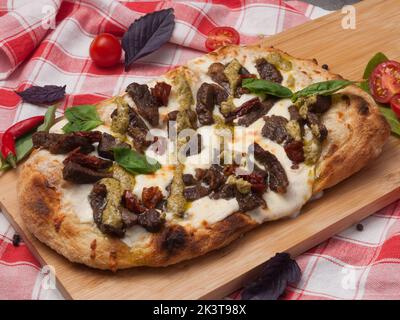 pizza savoureuse avec du bœuf et des tomates séchées sur une planche de bois Banque D'Images