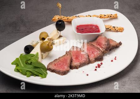 steak de bœuf en tranches avec assortiment de fromages et sauce aux baies Banque D'Images