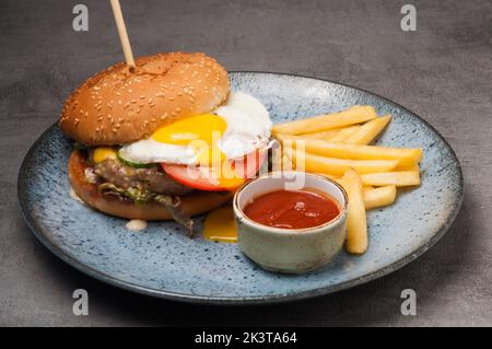 hamburger savoureux avec escalope de poulet et œuf avec frites et ketchup Banque D'Images