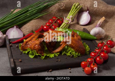 une savoureuse aile de poulet fumé décorée de légumes frais Banque D'Images