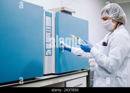 Portrait d'un scientifique portant des gants, un masque et un capuchon travaillant en laboratoire Banque D'Images