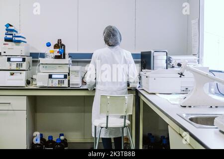 Vue arrière d'un médecin anonyme debout sur un ordinateur en laboratoire Banque D'Images
