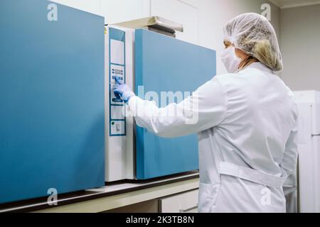 Portrait d'un scientifique portant des gants, un masque et un capuchon travaillant en laboratoire Banque D'Images