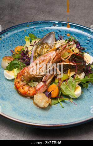 salade savoureuse avec légumes, langoustines, moules et pétoncles décorés d'œufs de caille. Gros plan Banque D'Images