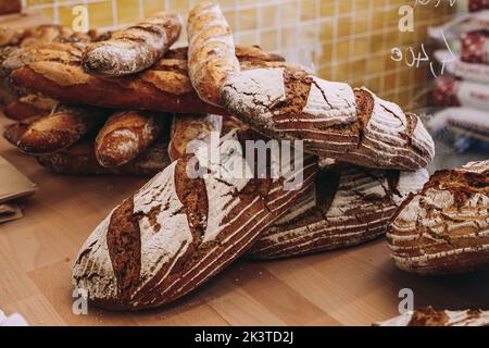 Gros plan de pains artisanaux fraîchement cuits à la croûte croustillante placés sur une table en bois dans la boulangerie Banque D'Images