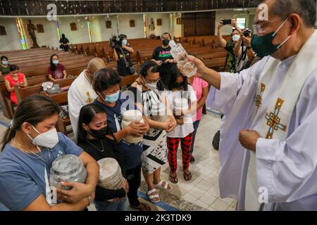 Manille, Philippines. 28th septembre 2022. Un prêtre arrose de l'eau sainte sur les membres de la famille et les parents des victimes de la guerre contre la drogue lors d'un service commémoratif à l'intérieur d'une église catholique de la ville de Quezon, dans la région métropolitaine de Manille, aux Philippines. 28 septembre 2022. Les restes ont été exhumés de leurs tombes après que le bail sur les tombes dans un cimetière public qu'ils ont été enterrés a expiré et les parents ne pouvaient pas se permettre de continuer avec elle. (Image de crédit : © Basilio Sepe/ZUMA Press Wire) Banque D'Images