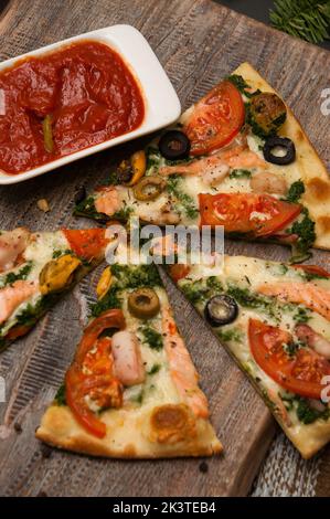 pizza savoureuse au saumon et au brocoli avec sauce tomate sur une planche de bois Banque D'Images