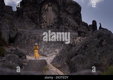 Vue arrière de la femme voyageur anonyme contemplant la statue de la Vierge dans les monts de Serra da Estrela Portugal Banque D'Images