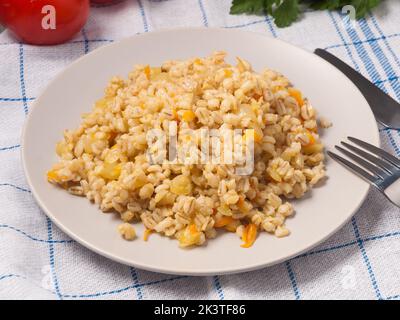 un savoureux porridge de perles avec des oignons et des carottes sur une assiette dans un café Banque D'Images