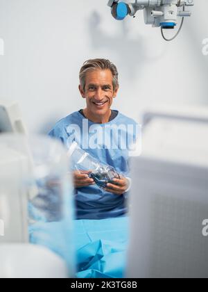 Homme mature en uniforme médical souriant et regardant la caméra tout en travaillant dans une clinique moderne Banque D'Images