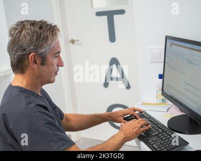 Vue latérale de l'homme mature en train de taper sur le clavier de l'ordinateur tout en travaillant dans le laboratoire de l'hôpital moderne Banque D'Images