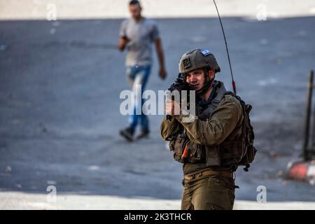 Hébron, Territoires palestiniens. 28th septembre 2022. Un soldat israélien cherche son arme lors d'affrontements avec des manifestants palestiniens dans la ville d'Hébron en Cisjordanie. Des manifestations et des affrontements ont éclaté en Cisjordanie à la suite du meurtre d'au moins quatre Palestiniens lors d'une opération militaire israélienne à Djénine. Crédit : Ilia Yefimovich/dpa/Alay Live News Banque D'Images