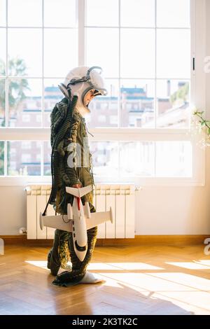 Adorable enfant avec un véritable uniforme d'astronaute. Il joue seul avec une navette spatiale à la maison Banque D'Images