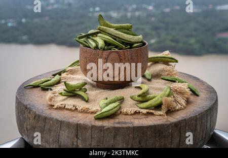 Pois mange-tout de sucre torréfiés sains dans un bol en bois sur une toile de raclage et un vieux bois rond sur fond de nature. Espace de copie pour le texte, mise au point sélective. Banque D'Images