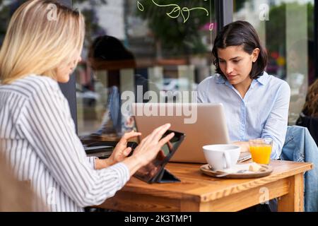 Photo moyenne de deux collègues de travail féminins et divers, axés sur leur travail dans un bureau extérieur Banque D'Images