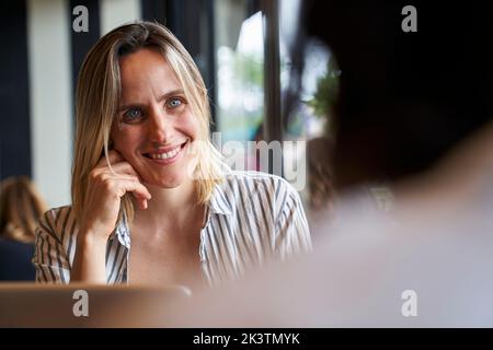 Photo de face moyenne d'une femme d'affaires attirante et du dos de ses collègues à la cafétéria de l'entreprise Banque D'Images